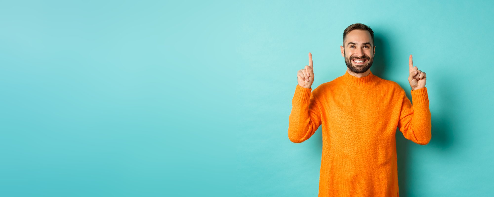 satisfied-happy-buyer-pointing-fingers-up-smiling-pleased-standing-orange-sweater-against-tur